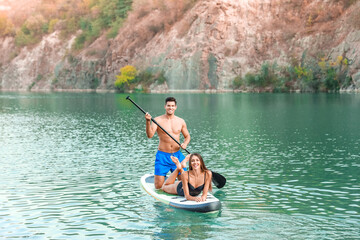 Young couple using paddle board for sup surfing in river