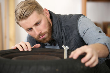 Obraz premium auto service man worker measuring rubber car wheel tyre protector