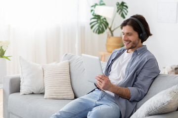 Happy guy with wireless headset and digital tablet at home