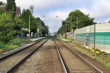 Fototapeta na wymiar Railway tracks with a small train station a protection wall and trees