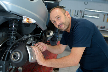 portrait of male mechanic working on scooter © auremar