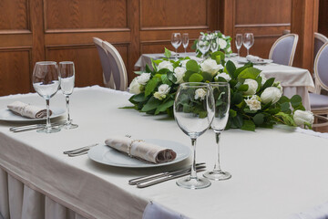 Glass wine glasses stand on the table against a background of flowers