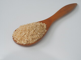 Coarse brown jasmine rice ( milled rice imperfectly cleaned, unpolished or half milled rice ) on wooden spoon background, Healthy food and diet concept.