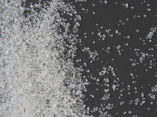 Close up white sugar on black background, warned that the sugar too much will make unhealthy nutrition, obesity, diabetes, dental care and much more.