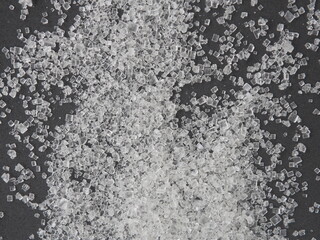 Close up white sugar on black background, warned that the sugar too much will make unhealthy nutrition, obesity, diabetes, dental care and much more.