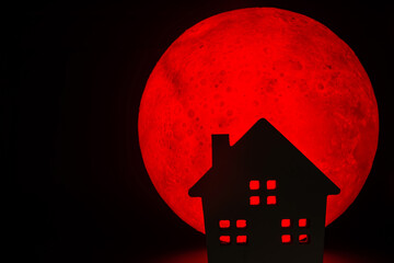 The silhouette of a Horror haunted house. There's a red full moon in the background. Halloween...