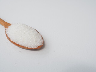 White sugar on wooden spoon and placed on white wooden background, Warned that the sugar too much will make unhealthy nutrition, obesity, diabetes, dental care and much more.