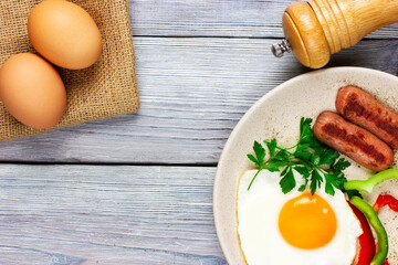 sunny side up. Fried eggs with sausages and vegetables on a light wooden table. Top view