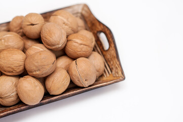 walnuts in a wooden bowl on a white background. 