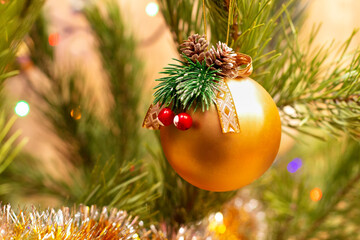 Decorative golden ball on the Christmas tree. Colorful decoration for New Years celebration.