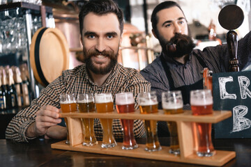 Man with beard smokes a pipe while standing at bar