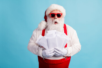 Portrait of his he nice attractive amazed stunned thick white-haired Santa holding in hand pile...