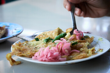 Spicy Egg Omelet on a white plate with Chilli and slice Onion 