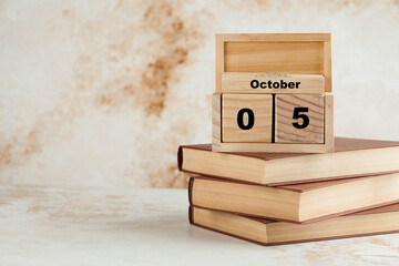 Wooden calendar October 5 on a stack of books. World teacher's day