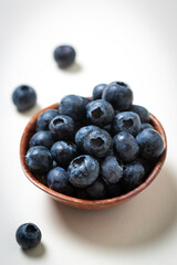 Close up of blueberries in a brown bowl on white background