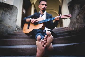 Street musician playing the guitar outdoors. Selective focus on feet. Music, art, creativity concept.