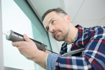 male worker using a silicone tube for repairing of window