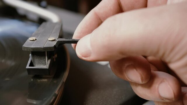 hands placing the vintage turntable on a spinning vinyl record. the vinyl record is spinning. the needle plays on a vintage vinyl record