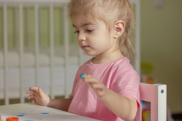 Cute little girl painting picture with fingers on home interior background.