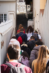Vertical shot of a group of tourists walking up narrow stairs going up hill to the Fortica castle above the city of Omis in Croatia. Students being led by a tour guide