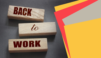 Coronavirus concept showing wooden blocks on a dark grey background reading Back To Work
