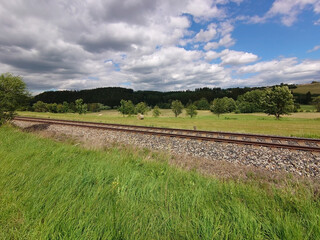 Empty railway track in countryside with blue sky