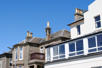 Fototapeta na wymiar Varied Roof Line & Chimneys on Old Buildings against Blue sky 