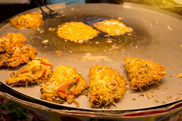 Crispy Thai style Oyster omelette with seafood on big hot pan at the food market in north Thailand, famous Thai snack, street food in Asia