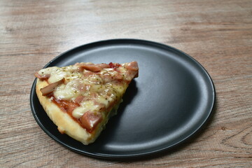 piece of pizza topping sausage and bacon with cheese on plate