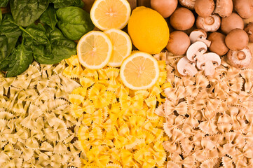 Multi-colored pasta with spinach, mushrooms and lemon. Typical cuisine of southern Italy. Dry Butterfly pasta with different flavors on a wooden background. High quality photo