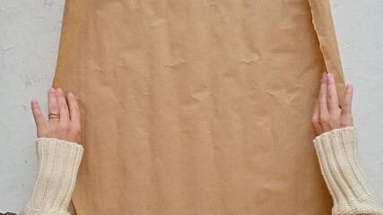 Female hands unroll gift wrapping paper and decorates by splashing white paint with a brush to imitate snow. Christmas crafts. Top view.