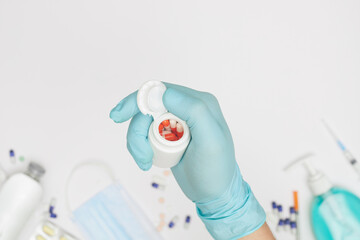 hand in glove with jar of capsules on white background covid-19 coronavirus prevention concept flat lay