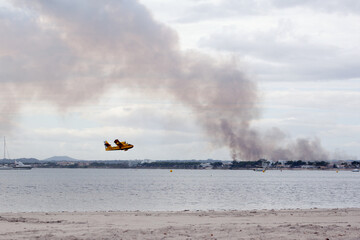 Fototapeta premium S'Albufera, Angry fire in S´Albufera in Mallorca, Balears, 26th September 2020, Alcudia, airplan under sea, the plane puts out the fire in Majorca, Spain, the area between Muro and Can Picafort