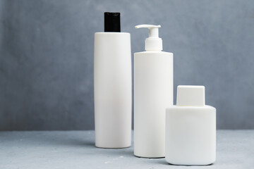 Skin, body and hair care concept. Templates of a bottles for cosmetics on gray background.