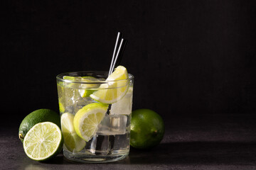 Caipiroska cocktail with lime in glass on black stone. Copy space