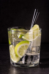 Caipiroska cocktail with lime in glass on black stone