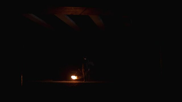 The man swings the fire rope and spins it over his head and around him. Fire-show
