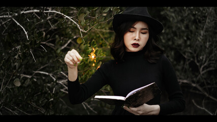 Portrait of asian wizard with magic wand and spell book - halloween theme.