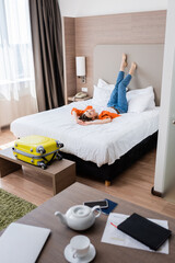 selective focus of barefoot young woman resting on bed in modern hotel room