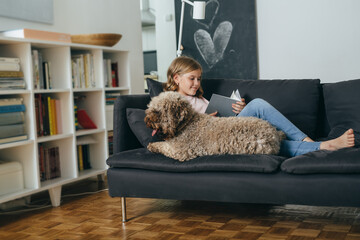 young girl with her dog at home reading book