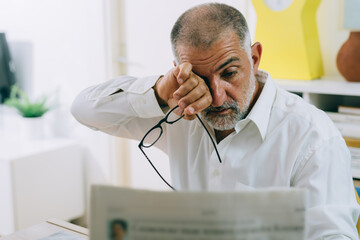 middle aged man reading newspapers having eyes problem