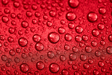 Red wet drops on a glitter surface. Abstract stock photography. Macro droplets of water