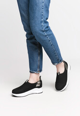 Woman legs in black sneakers on a white background.Concept of an advertising photo for shoes
