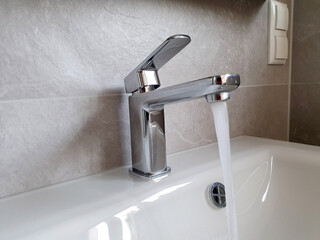 Fliesendes Wasser aus dem Wasserhahn in ein Waschbecken