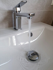 Fliesendes Wasser aus dem Wasserhahn in ein Waschbecken