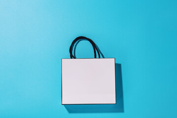 Empty white shopping bag on blue background, top view