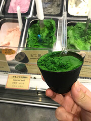 ice cream green flavor frozen dessert pattern in black cup hand holding on wood.