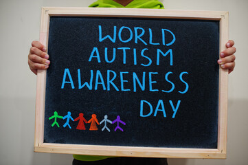 World autism awareness day. Boy hold chalkboard with blue inscription.