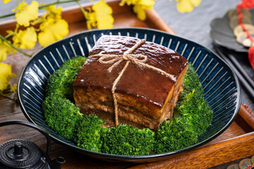 Dong Po Rou (Dongpo pork meat) in a beautiful plate with green vegetable, traditional festive food for Chinese new year cuisine meal, close up.