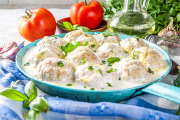 Homemade creamy white chicken meatballs. Classic Swedish meatballs with creamy cheesy sauce, with parmesan cheese and parsley, in skillet on grey stone table background